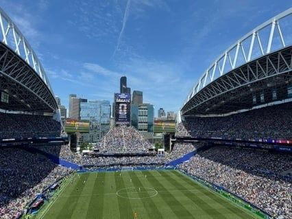 Fullsatt fotbollsarena med publikflöden runt planen och läktarna